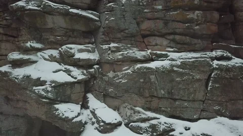 A drone rises above a snow-capped rock in a canyon in winter. Video stock 147627738