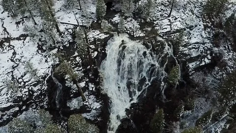 Drone rises above waterfall surrounded by snow Stock Footage 83229681