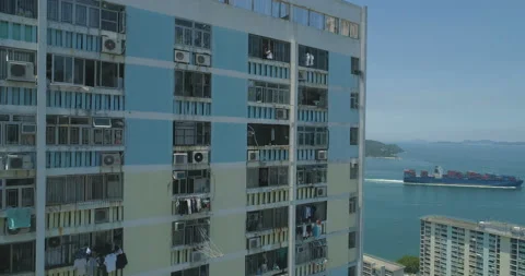 The drone rises along the facade of an apartment building with cargo ship on Stock Footage 116232637