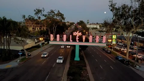 Drone rises and descends in front of The Boulevard neon sign as full moon rises Stock Footage 97159858