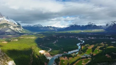 Drone rises and shoots Bow River and valley with mountains on the horizon Video stock 137513897