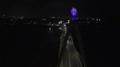 Drone rises up to gem on main pillar at night on colorfully lit up bridge Stock Footage 342254716