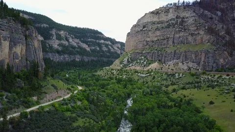 Drone rises high over a canyon cutting through dramatic mountain cliffs in Stock Footage 104716750