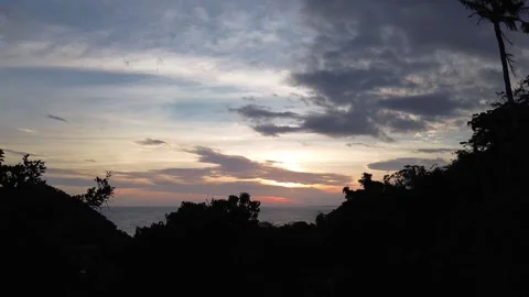 Drone rising above forested mountain revealing sunset Apo Island Philippines Video stock 332615775