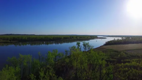 Drone rising above sparse tree line reveals grand calm Missouri river Stock Footage 247329934