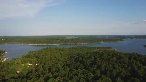 Drone rising above trees at sunset with boats running across a lake Stockbeeldmateriaal 200981851