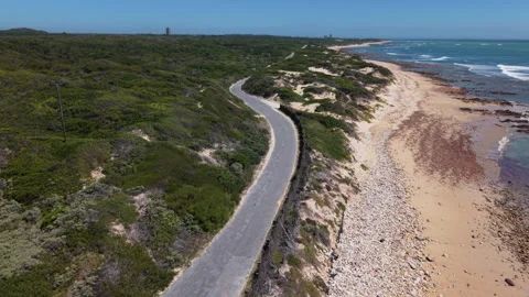 Drone Rising from Beach Pebbles and Rocks to Reveal Green Landscape, Coastal Roa Stock Footage 306330559