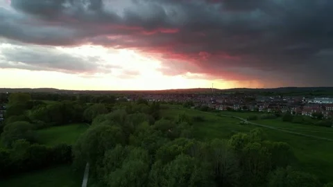 Drone rising over fields and housing estate at sunset with storm clouds Stock Footage 242615328