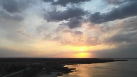 Drone rising over a large lake at sunset.  The sky is a mixture of bright orange Stock Footage 263583709