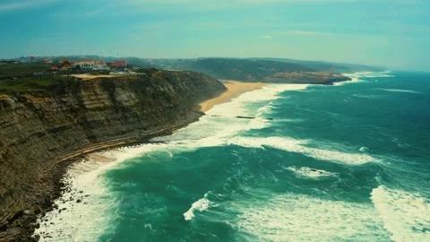Drone is rising over ocean with flying birds near rocky coastline in Ericeira Stock Footage 197268103