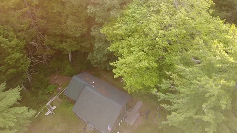 Drone Rising Over Rustic Log Cabin Toward Sun Flares over Trees Stock Footage 129456754