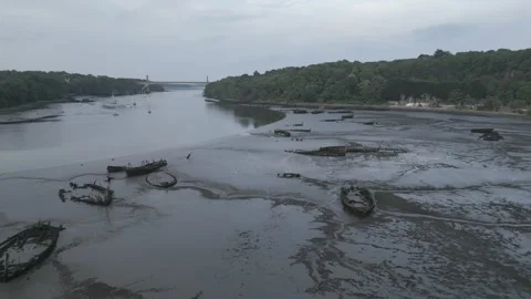 Drone Rising Over Ship Graveyard, Revealing River &amp; Distant Bridge, France Stock Footage 302565514