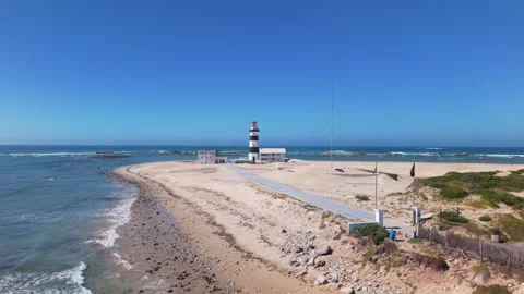 Drone Rising with View of Lighthouse, Ocean, Beach, Sand, Blue Sky, and Waves wi Stock Footage 306292957