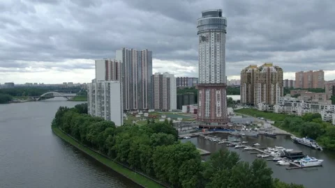 Drone rising while circling high rise near river Vídeos de archivo 332684128