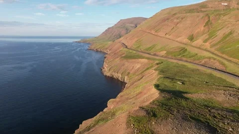 Drone rotate over coastal mountain road and ocean in evening sun, Iceland Stock Footage 346552345