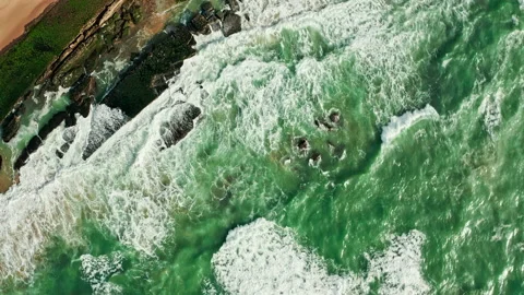Drone  rotates and rises over the surface of the water along the rocky shore. Stock Footage 197558188