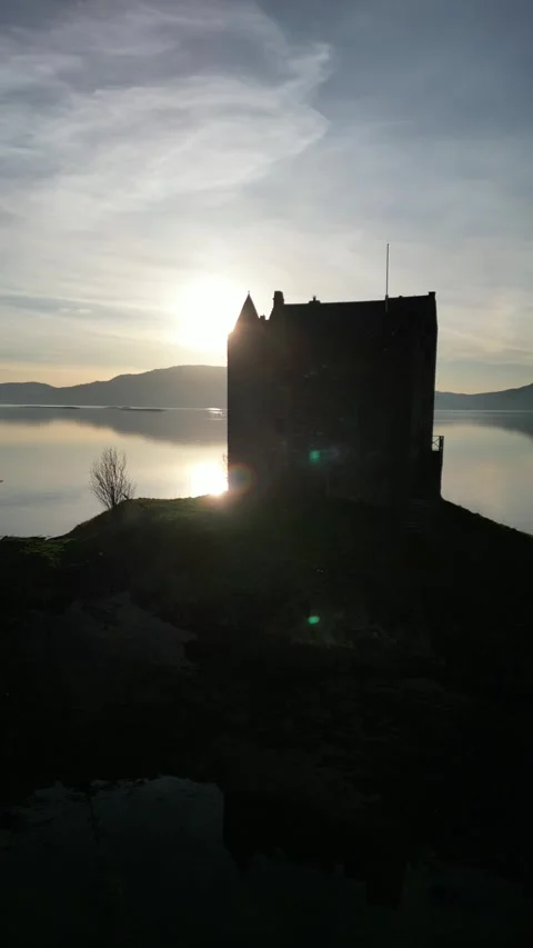 Drone rotating around island castle revealing sun in Scotland 動画素材 334459879