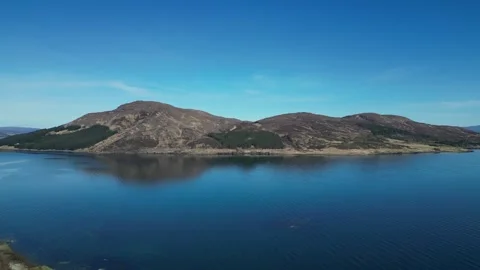 Drone rotating left over lake and hills in Scotland 動画素材 334458673