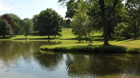 Drone Rotating Tracking Shot of Park Bench Next To Pond Stock Footage 273500572