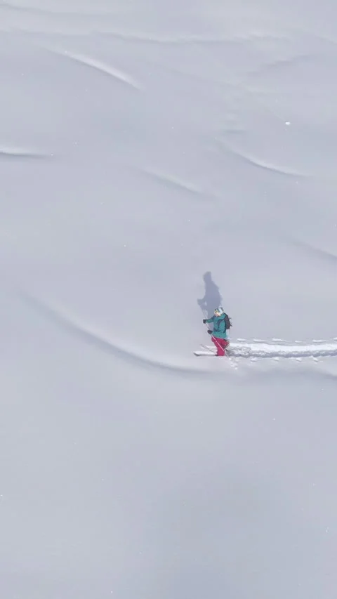 DRONE: Scenic drone shot of wintry landscape surrounding a female ski tourer. Stock Footage 281035938