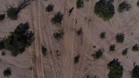 Drone shooting straight down on desert landscape dirt bikes races through frame Stock Footage 104883870