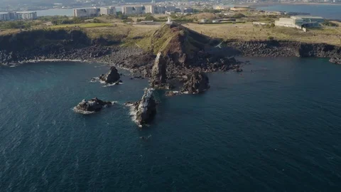 A drone shooting a white lighthouse standing on the edge of a cliff overlooking  Stock Footage 122061587