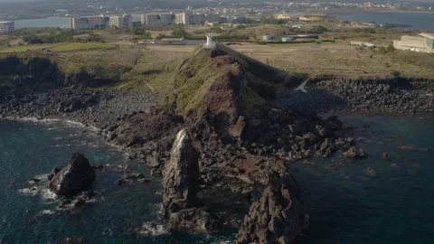 A drone shooting a white lighthouse standing on the edge of a cliff overlooking  Stock Footage 122061680