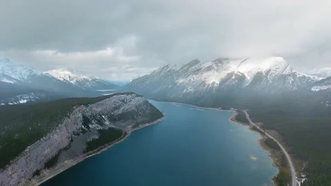 Drone shoots the cloudy sky and snowy peaks reflected in Spray Lakes Reservoir Video stock 137511580