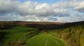 Drone shot aerial fly over sunny green farmland valley in early spring 4k or 4k+ Resolution