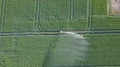Drone shot aerial irrigation traveling sprinkler on green field with tracks 4k or 4k+ Resolution