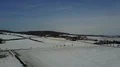 Drone shot aerial street in snowy farmland winter landscape low mountain range 4k or 4k+ Resolution