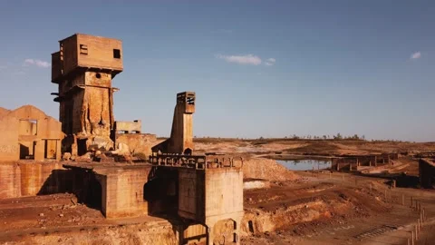 Drone shot aerial view post-apocalyptic desert mining ruins by a lake Stock Footage 159511090