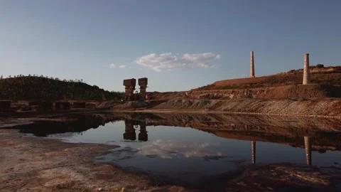 Drone shot aerial view post-apocalyptic desert mining ruins by a lake Stock Footage 159511532