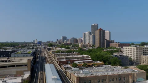 Drone shot along Chicago's elevated CTA tracks toward a cluster of lakefront Stock Footage 346384151