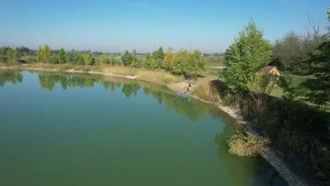 Drone shot of angler casting out from the shore next to a bush Stock Footage 227742965