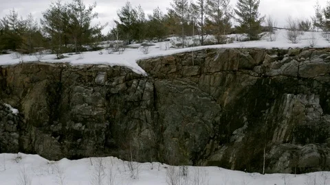 Drone shot ascending a rock cliff face on the side of a road Видео 120652853
