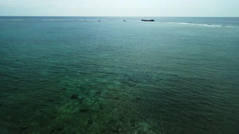 Drone shot backward over the emeral green sea Stock Footage 196442135
