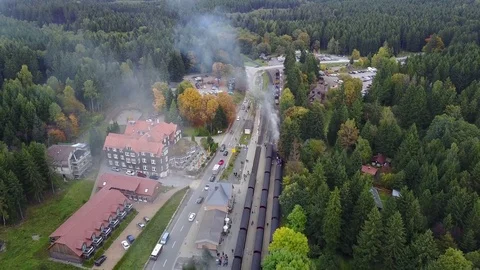 Drone shot backwards aerial little mountain forest station with steam locomotive Stock Footage