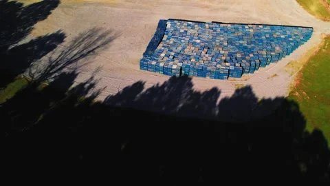 Drone Shot of Blue Pallet Stack Casting and Long Tree Shadows on Gravel Lot Stock Footage 307171774
