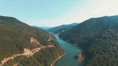 Drone shot of a blue river between two hills covered in forests Stock Footage 129849577