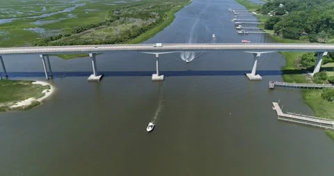 Drone shot of boat going under Sunset Beach Bridge on the Intercoastal Waterway  Stock Footage 202343478