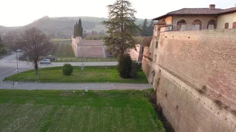 Drone Shot of Bus and Red Van Exiting Red Brick Castle in Italian Village Stock Footage 304843838