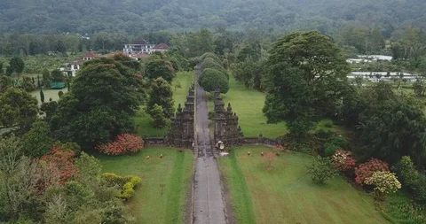 Drone shot of Candi Bentar split gates on roadside amidst trees in village Stock Footage 96228181