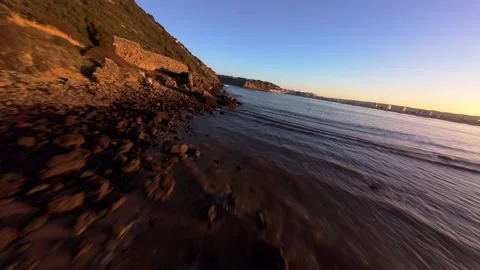 Drone shot captures serene coastline with soft waves and warm light Stock Footage 344580373