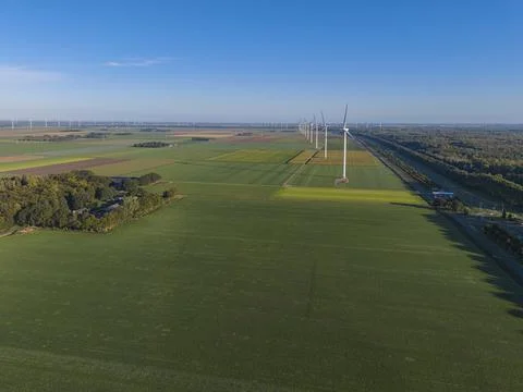Drone shot captures wind farm amid lush green fields and tree-lined road Foto stock