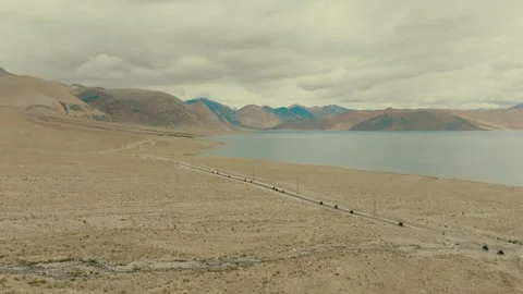 Drone shot capturing adventure riders alongside the serene and scenic Pangong Stock Footage 310899227