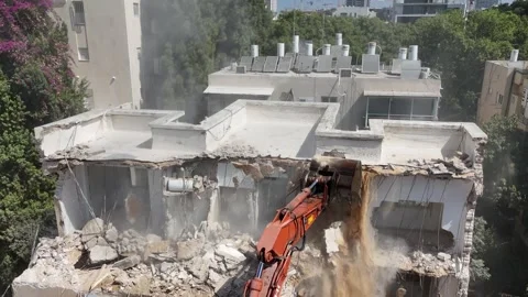Drone shot capturing the destruction of a building by a massive bulldozer Stock Footage 294261791