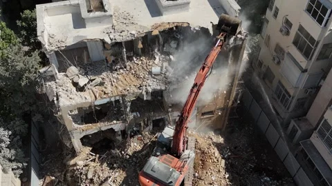 Drone shot capturing the destruction of a building by a massive bulldozer Stock Footage 294723085