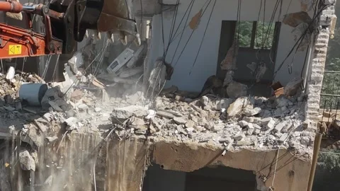 Drone shot capturing the destruction of a building by a massive bulldozer Stock Footage 294723089
