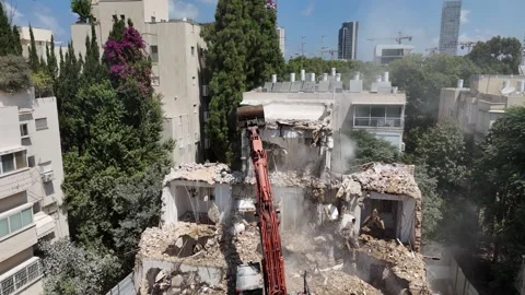 Drone shot capturing the destruction of a building by a massive bulldozer Stock Footage 294723138
